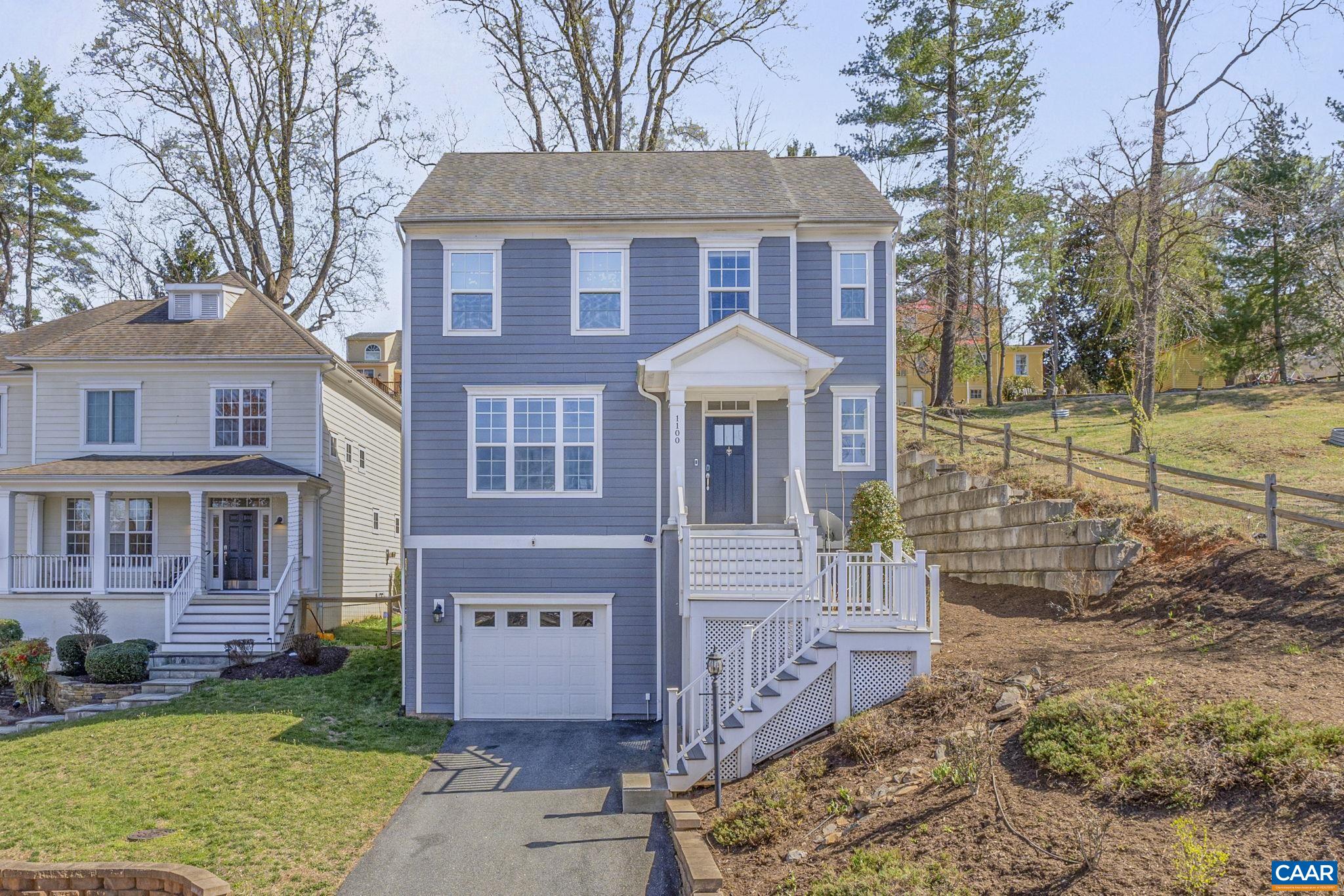 Blue two-story house with a white porch and garage on a sloped lot.