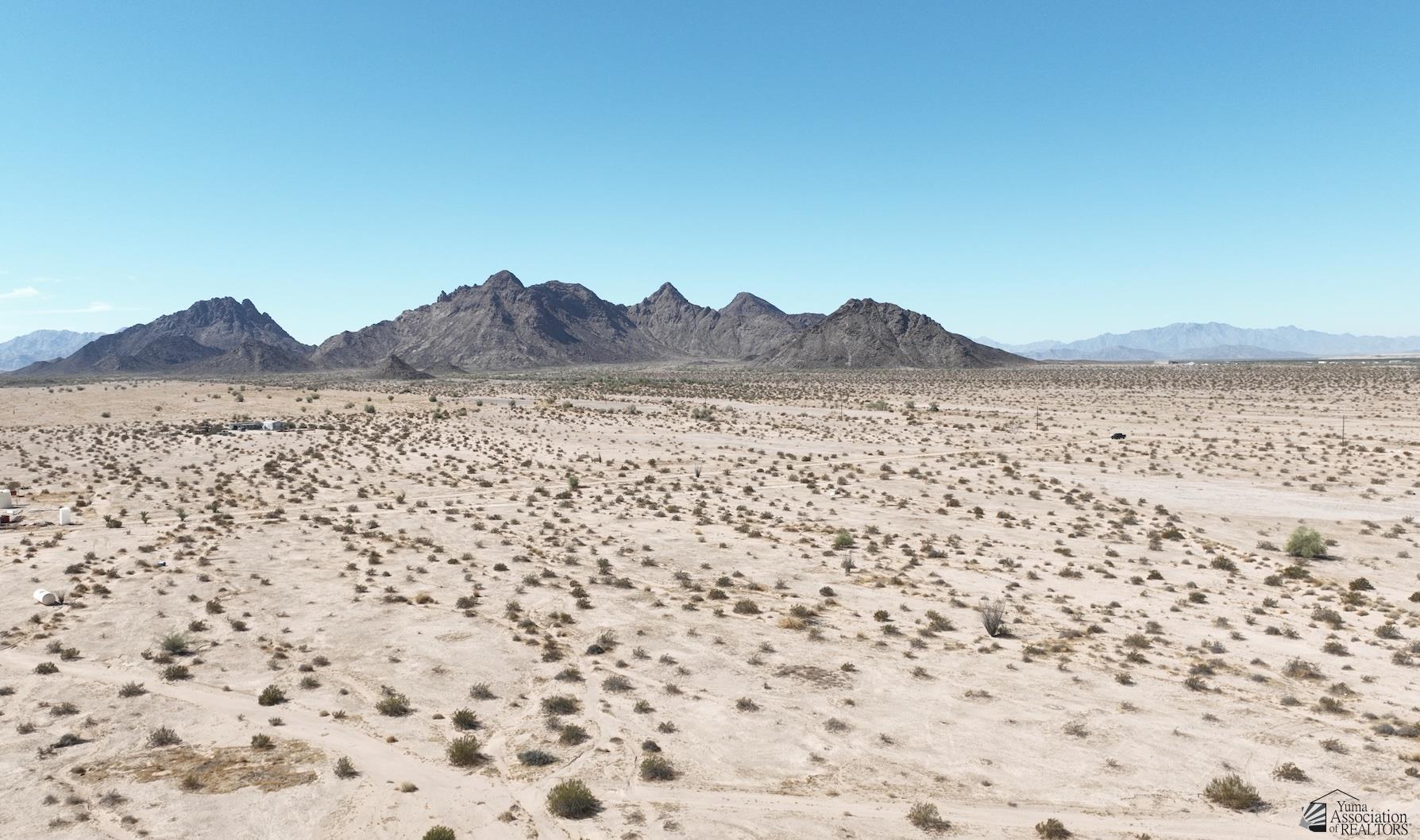 Aerial view of sparse desert land with rugged mountains across the horizon.