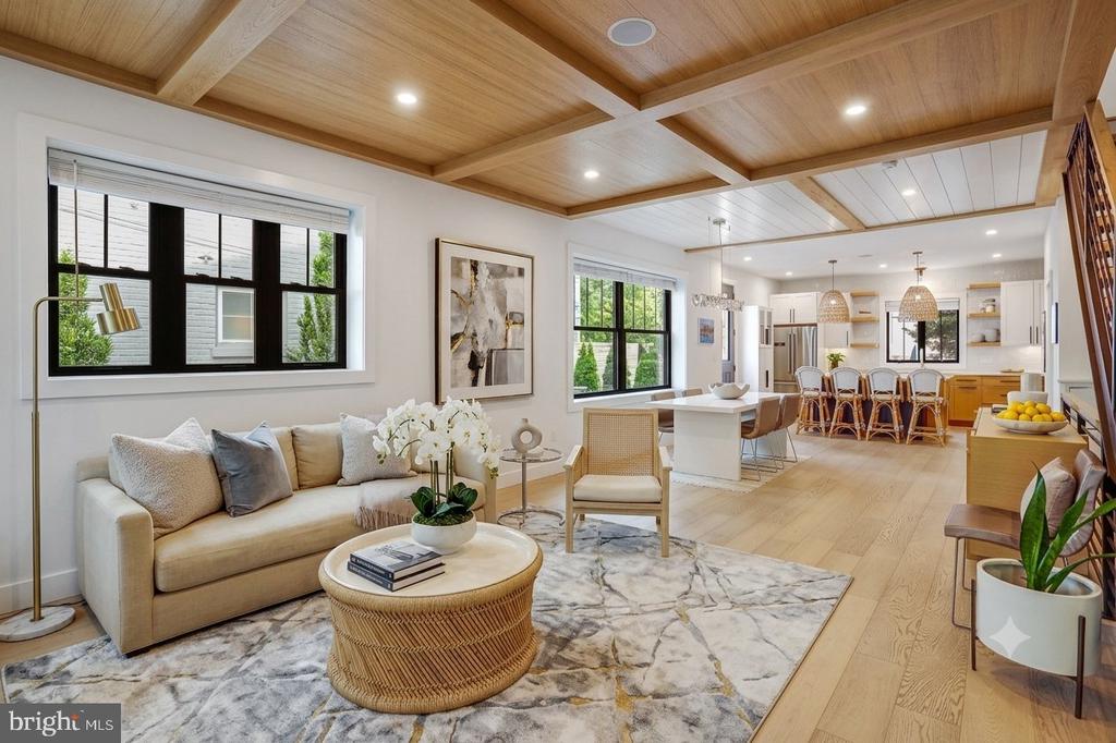 Open-plan living room and kitchen with a coffered wood ceiling and large black-framed windows.