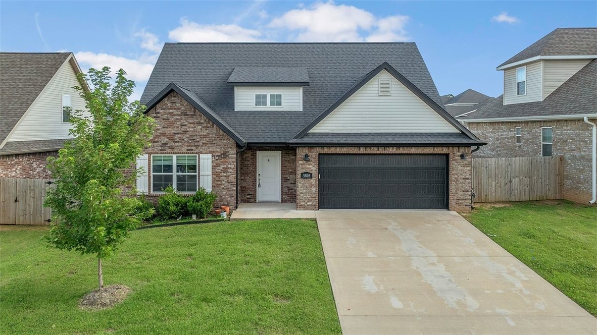 Brick-and-siding house with a two-car garage, broad driveway, and green front lawn.