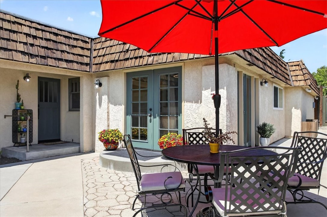 Home patio with teal French doors, black dining set, and a large red umbrella.