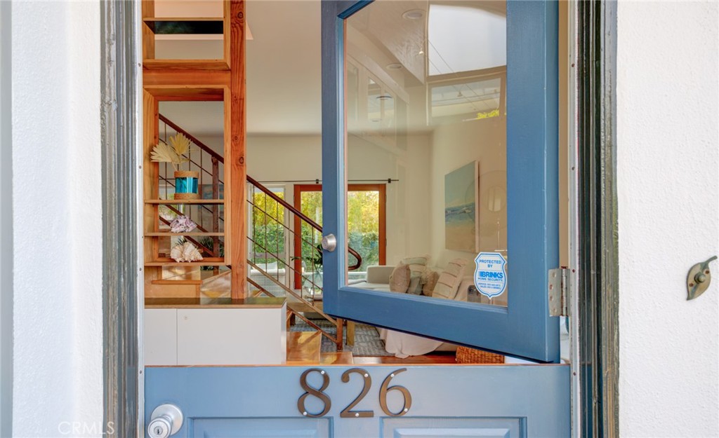 Blue front door marked 826 opens onto a bright interior with a wood staircase and furnished living area.