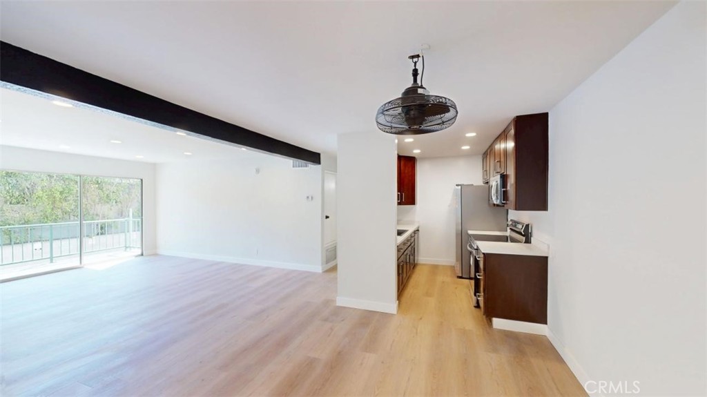Open-plan living room and kitchen with dark cabinetry and sliding doors to a balcony.