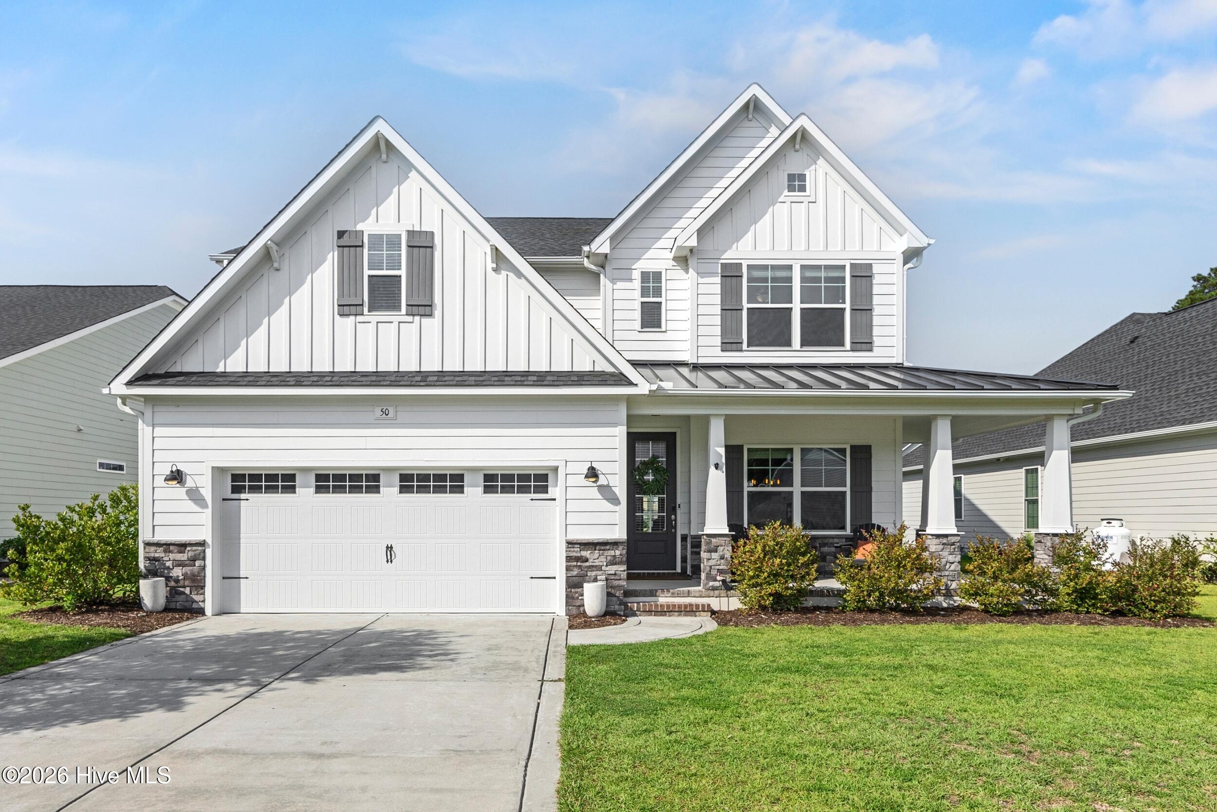 White two-story home with a two-car garage, covered porch, and gabled roof.