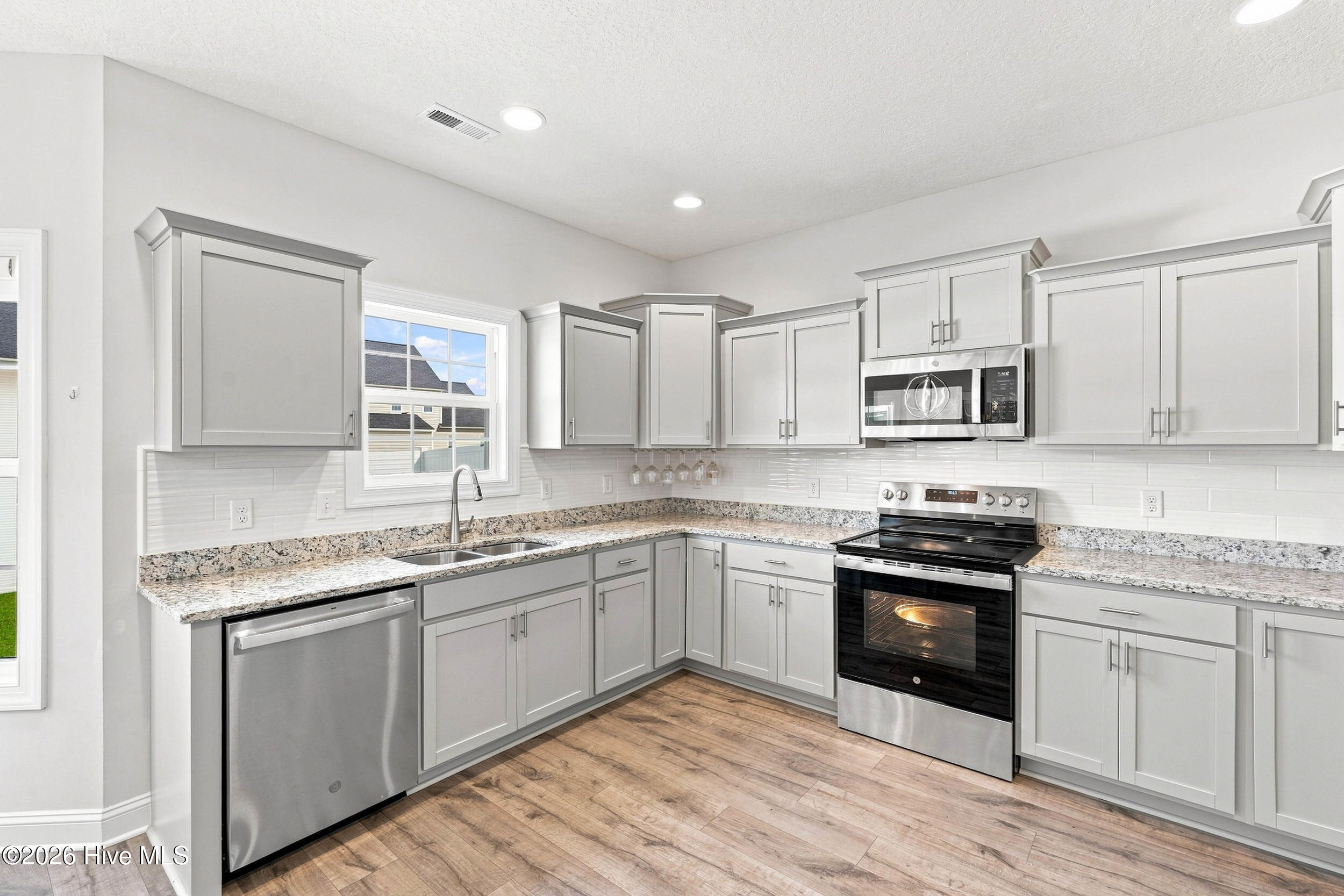 Kitchen with gray shaker cabinets, granite counters, and stainless steel appliances.