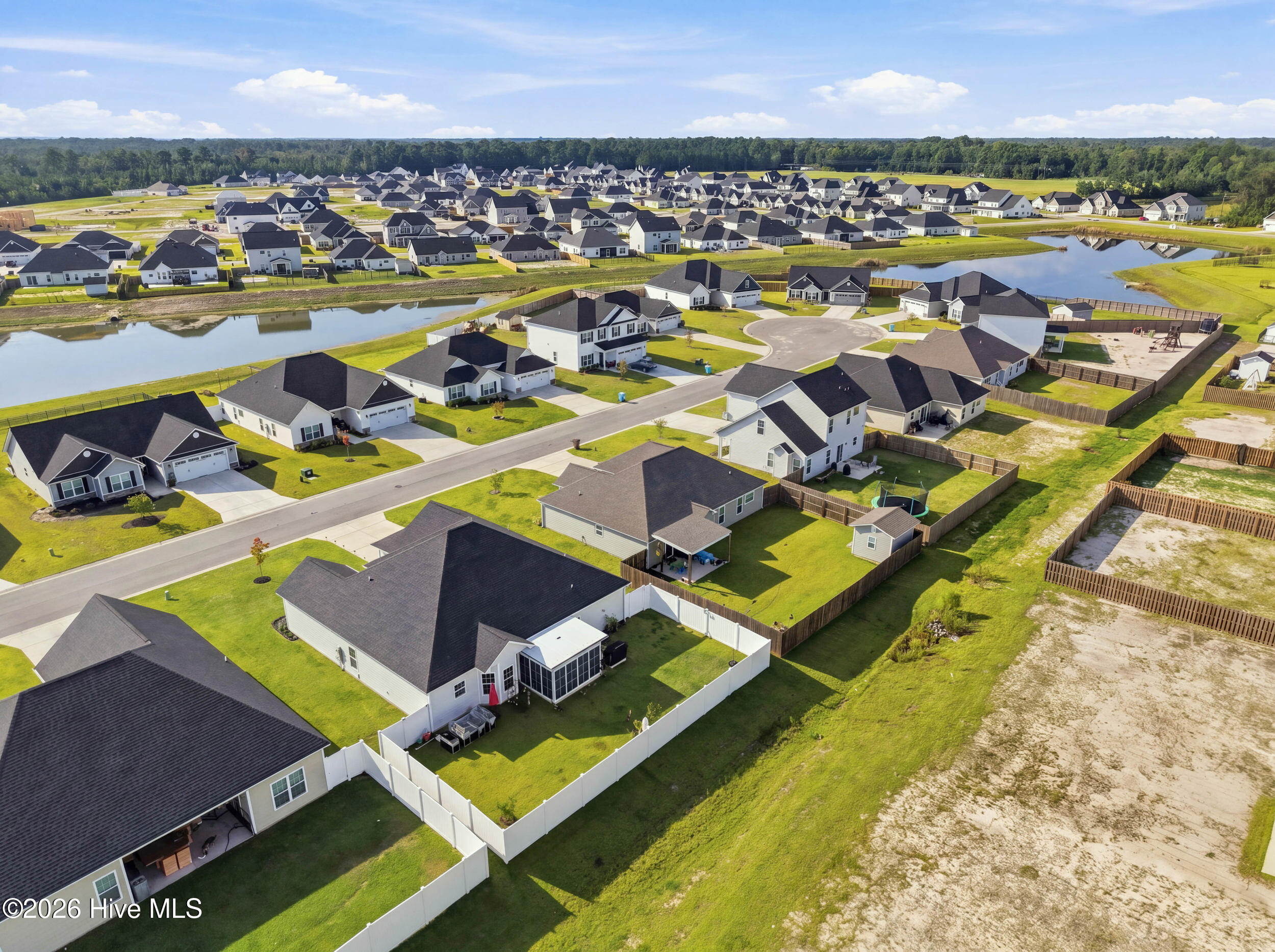 Aerial view of homes with fenced lawns beside neighborhood ponds.