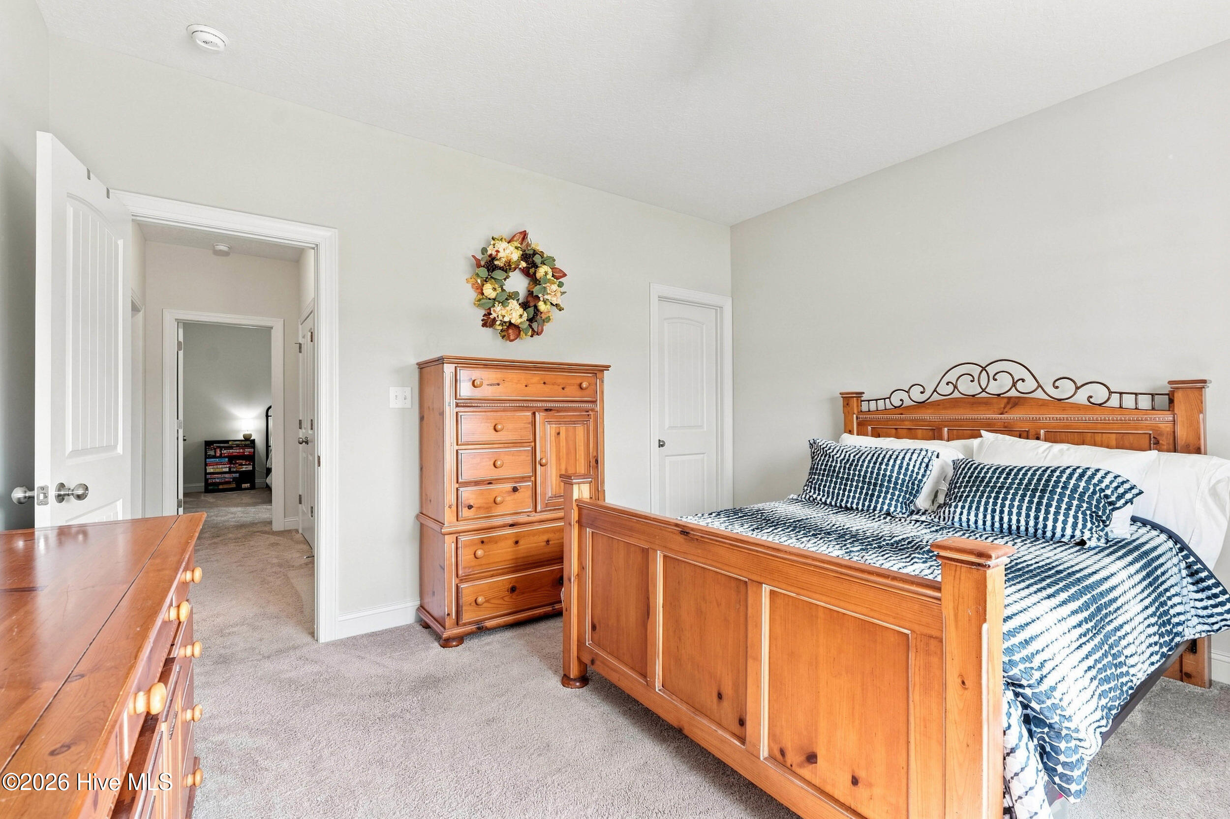 Furnished bedroom with a wooden bed, blue-and-white bedding, and matching dresser.