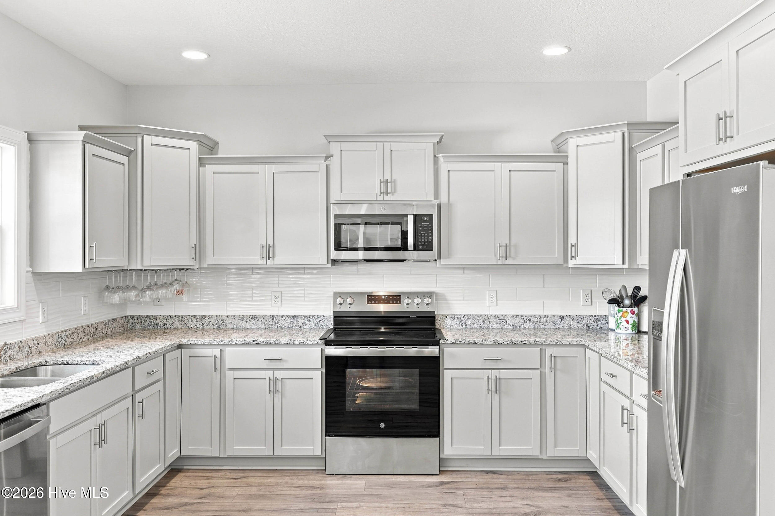 Kitchen with white cabinets, granite countertops, and stainless steel appliances.