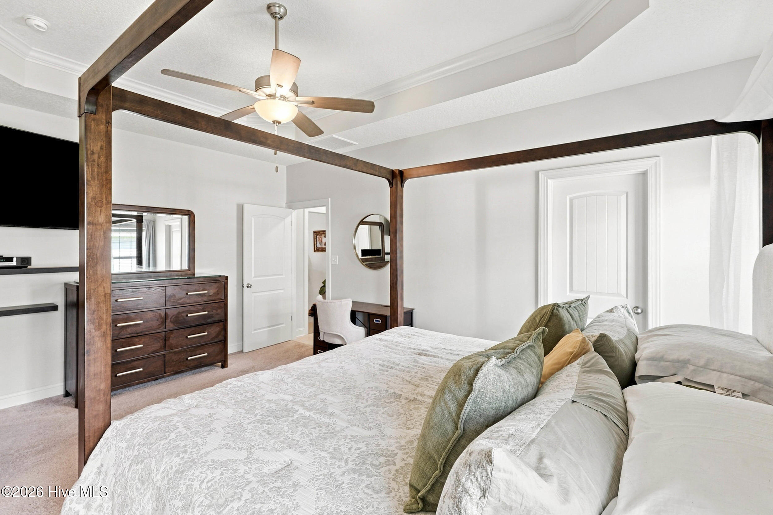 Bedroom with a dark wood canopy bed, patterned bedding, and a ceiling fan.