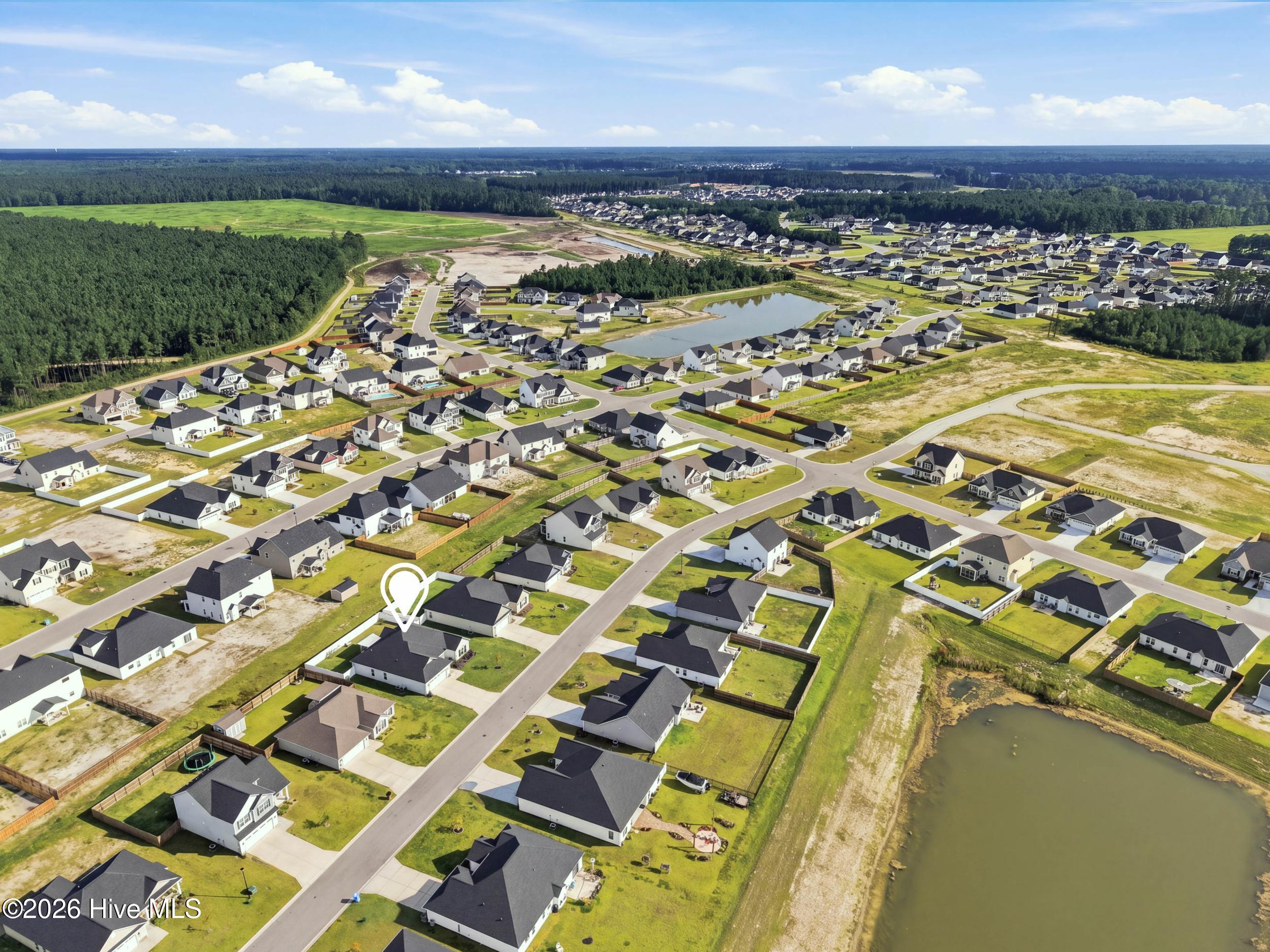 Aerial view of a home marked within a neighborhood beside a pond.