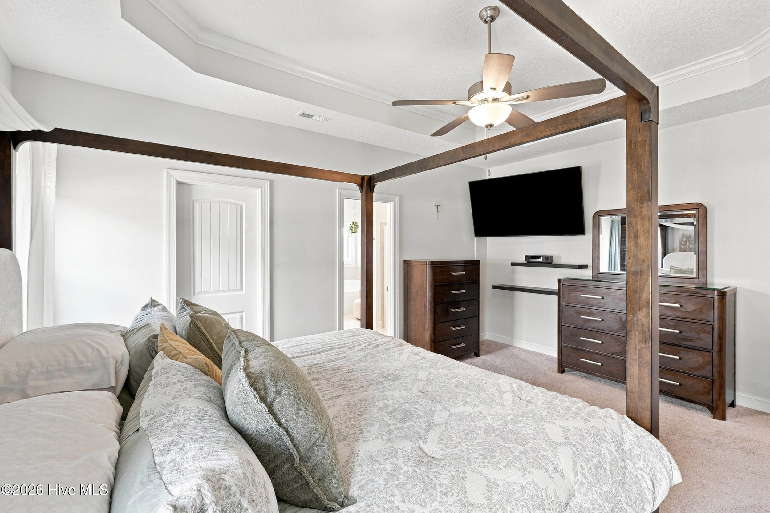 Bedroom with a dark wood four-poster bed, patterned bedding, and wall-mounted television.