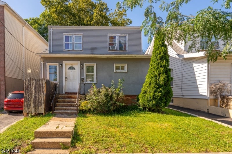 Gray two-story house with white trim, front steps, and a small lawn.