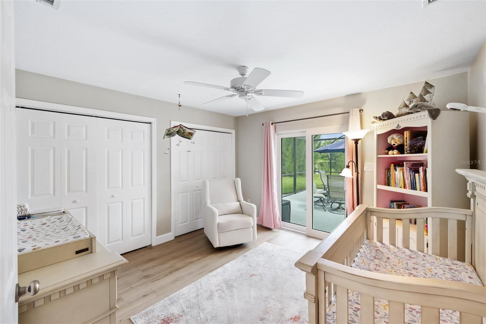 Bedroom with a wooden crib, changing table, and sliding glass doors to a patio.
