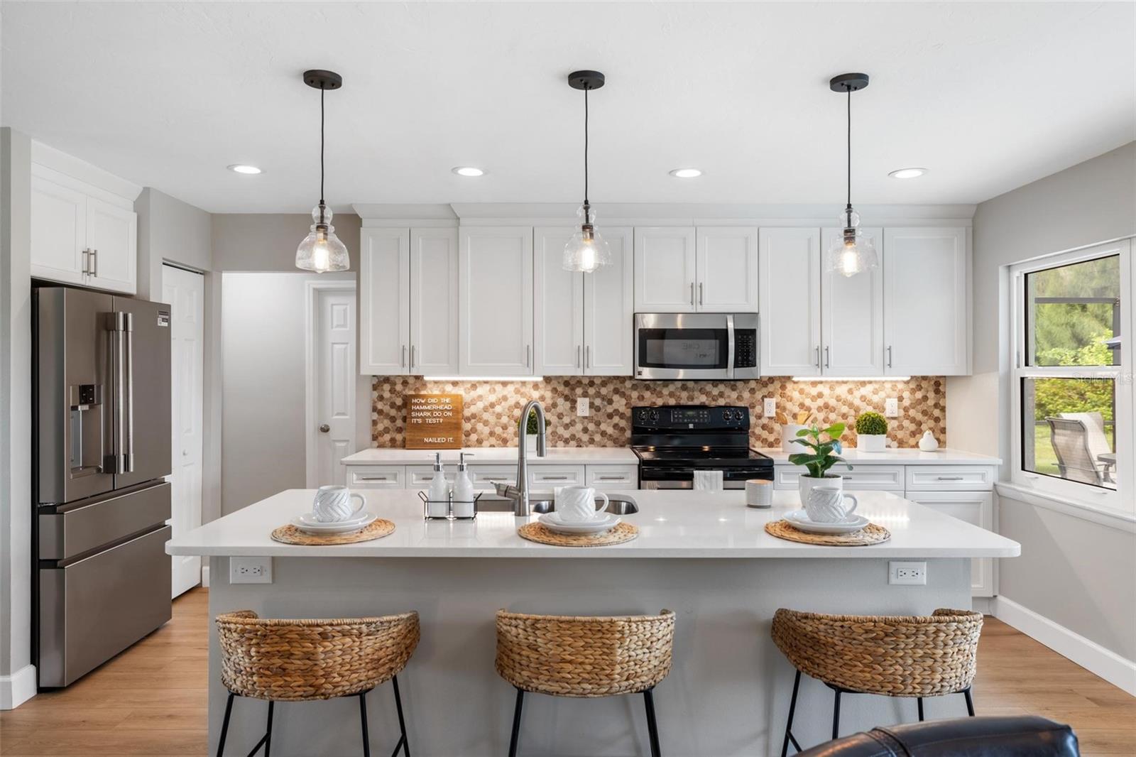 Bright kitchen with a white island, woven stools, white cabinets, and a patterned backsplash.
