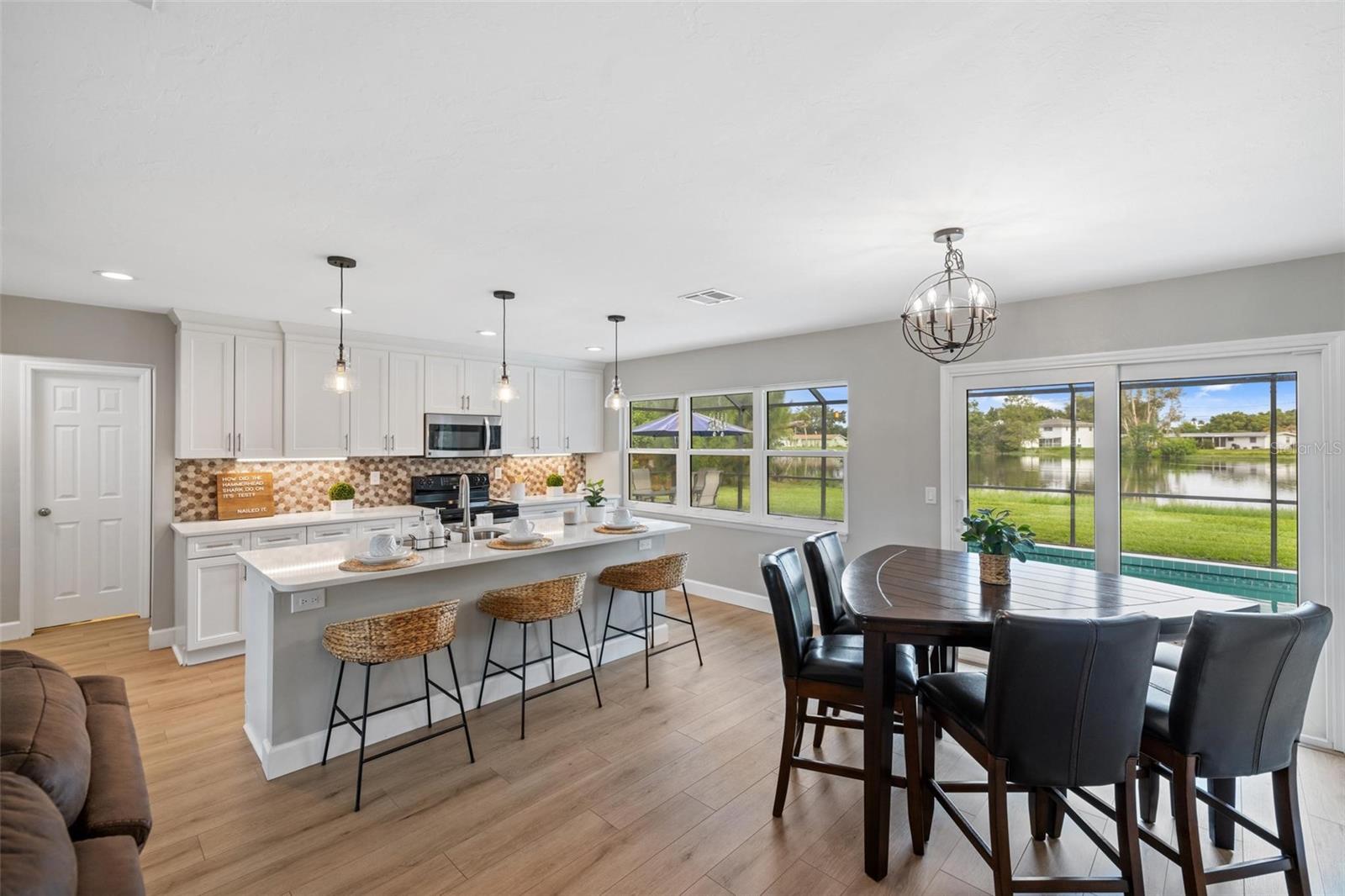 Open kitchen and dining area with a large island and pond views through sliding glass doors.