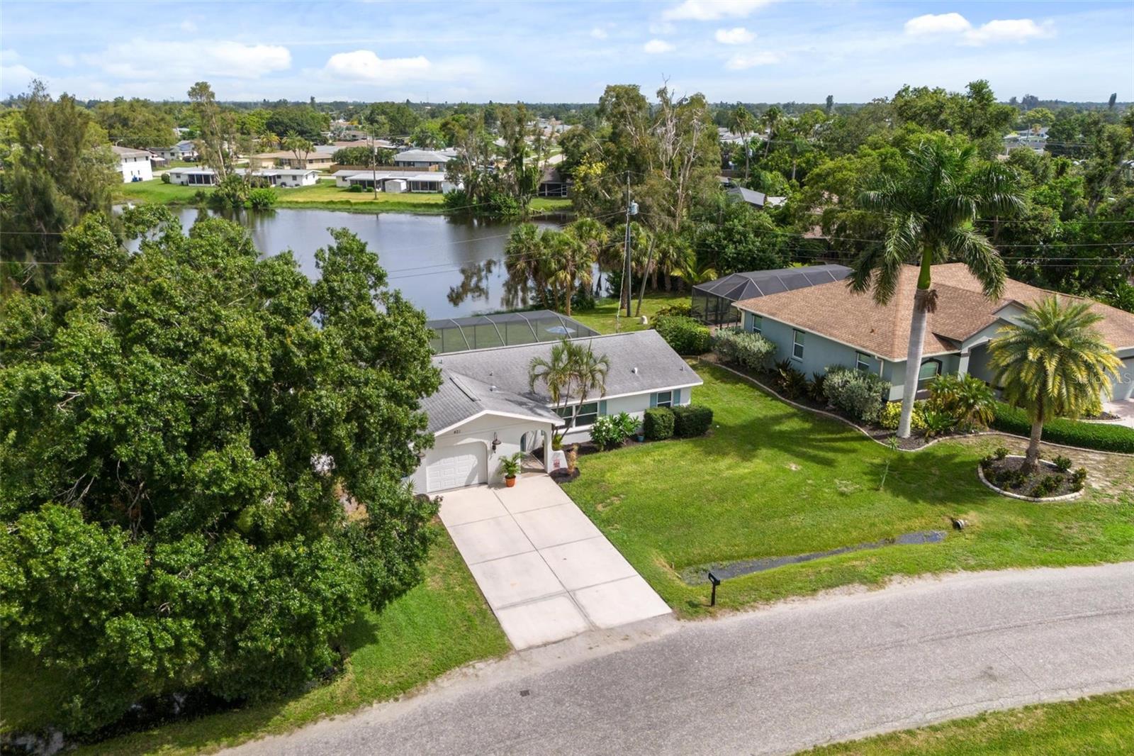 Aerial view of 421 Morningside Road, showing its screened pool, lawn, and waterway behind the home.