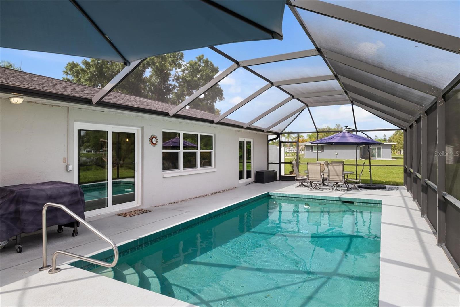 Screened pool patio with turquoise water, sliding glass doors, and outdoor dining furniture.