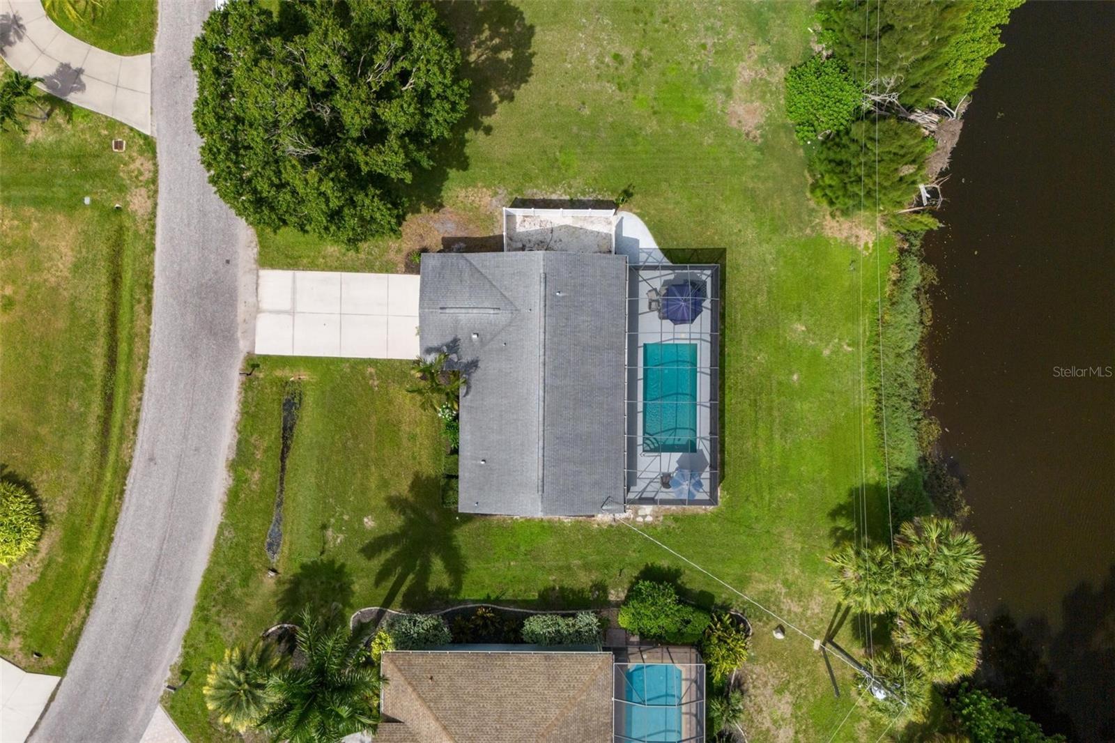 Aerial view of a home with a screened pool beside a canal.
