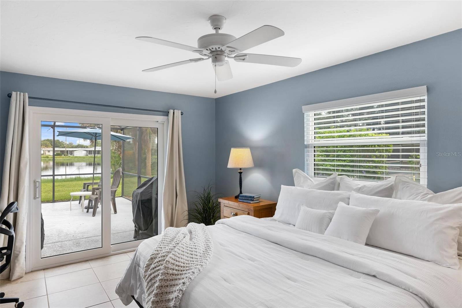 Bedroom with a white bed and sliding doors overlooking a patio and waterway.