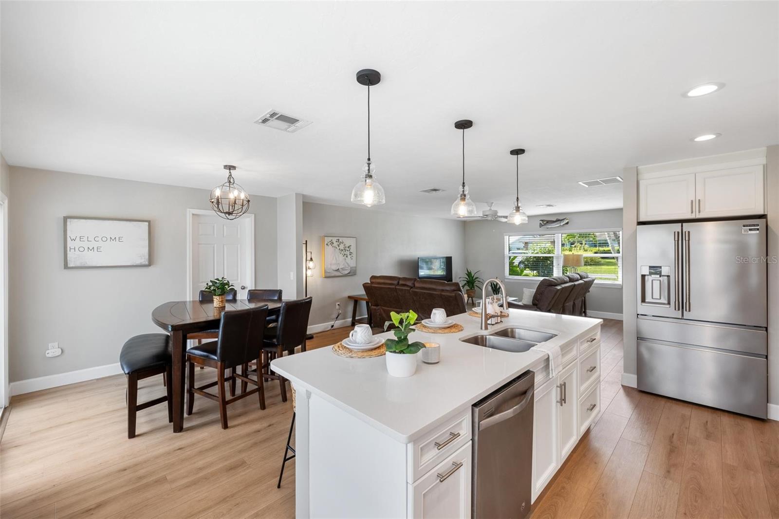 Open-plan kitchen with a large white island, stainless steel appliances, and dining and living areas beyond.