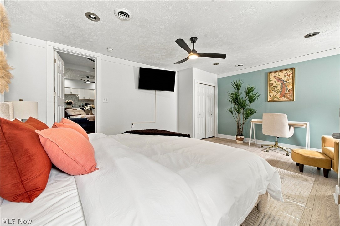 Furnished bedroom with a white bed, coral pillows, and teal accent wall.