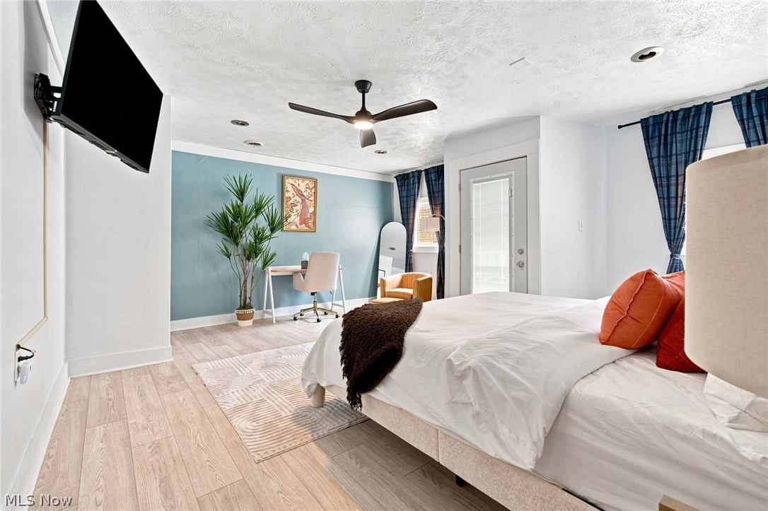 Furnished bedroom with a blue accent wall, white bed, and orange pillows.