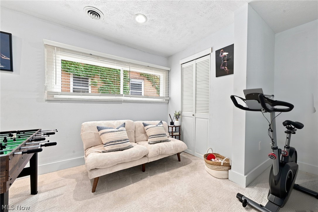 Recreation room with a cream sofa, foosball table, and exercise bike.