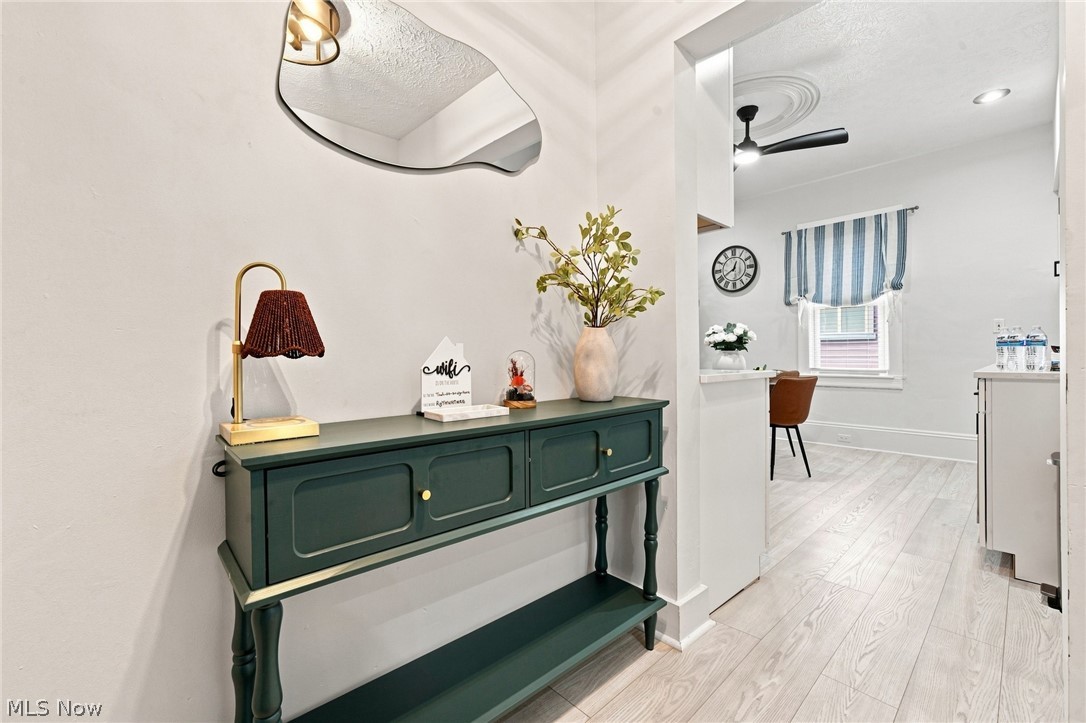 Entry hall with a dark green console table and mirror, opening into a bright dining area.