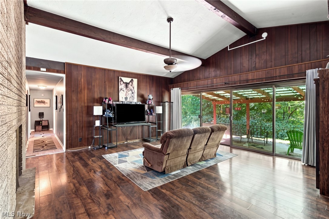 Living room with wood-paneled walls, a stone fireplace, and sliding doors to a covered patio.