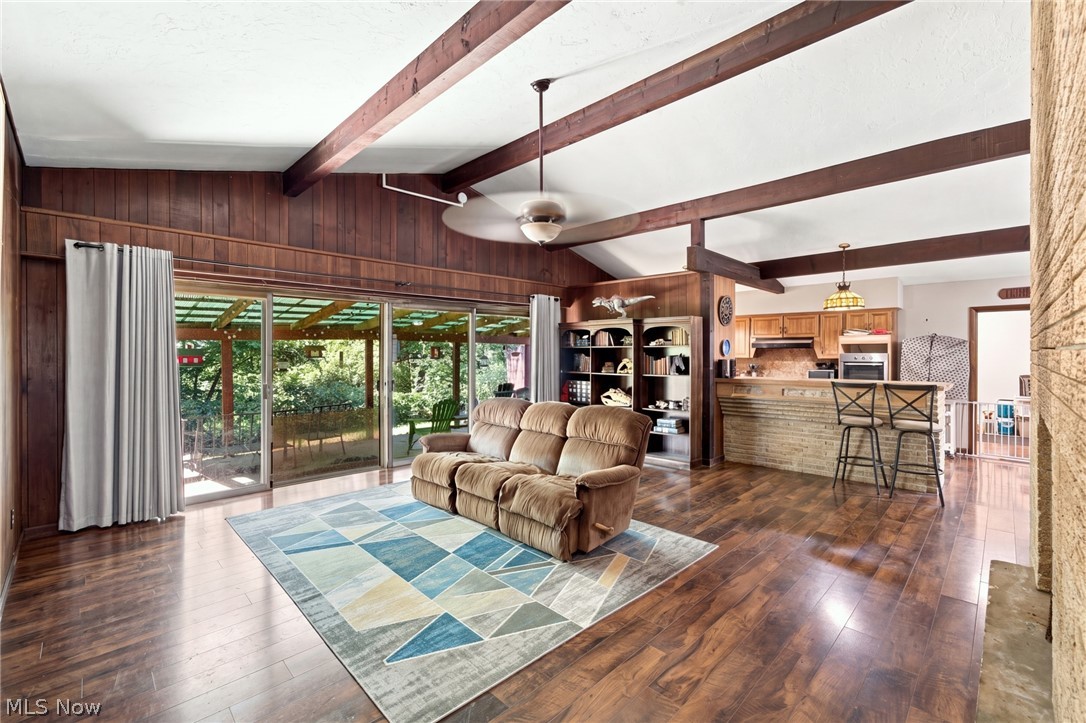 Living room with exposed wood beams, a geometric rug, and sliding doors to a covered patio.