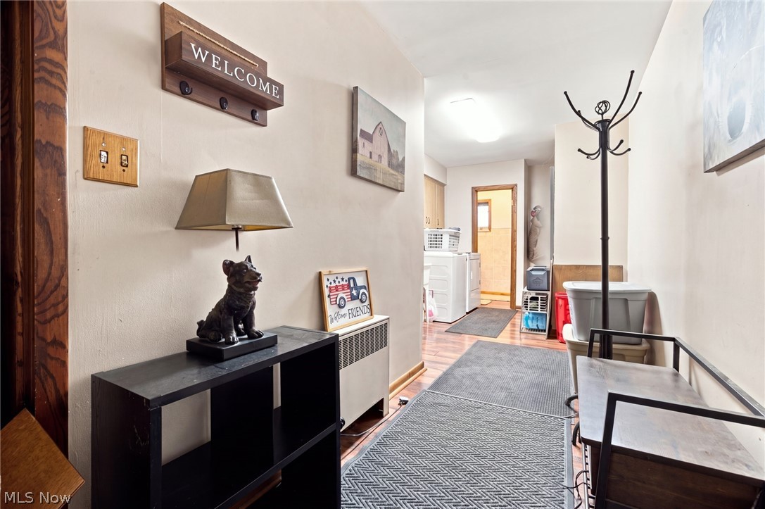 Furnished hallway with a patterned runner, black console table, coat rack, and laundry area.