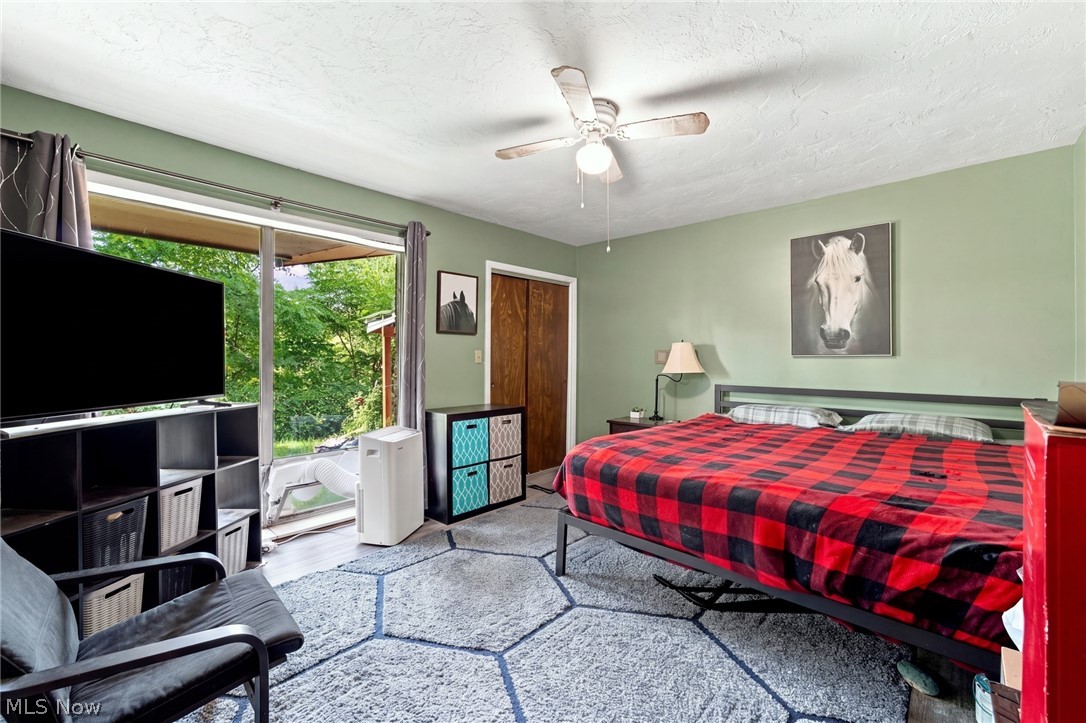 Bedroom with a red-and-black plaid bed, sage-green walls, and sliding glass doors overlooking greenery.
