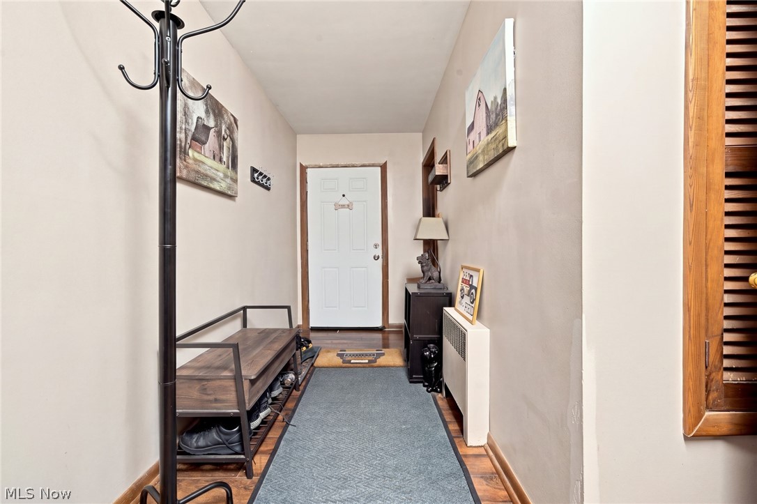 Entry hallway with a blue runner rug, wooden shoe bench, and white front door.