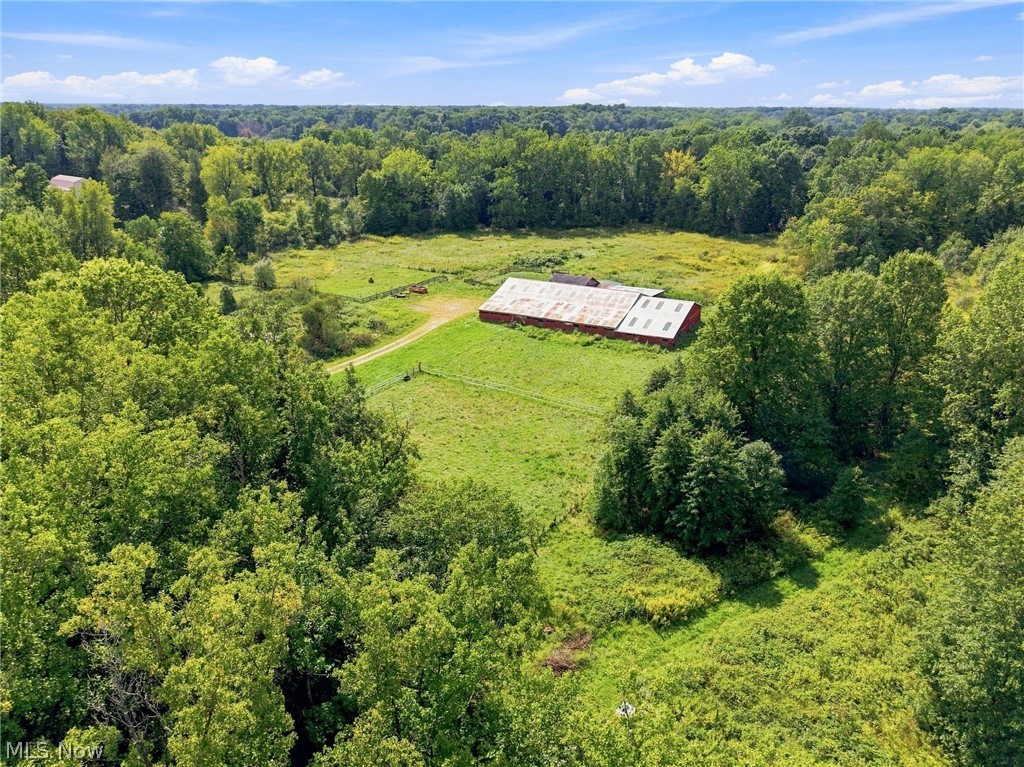 Aerial view of a barn amid open fields and dense woodland.