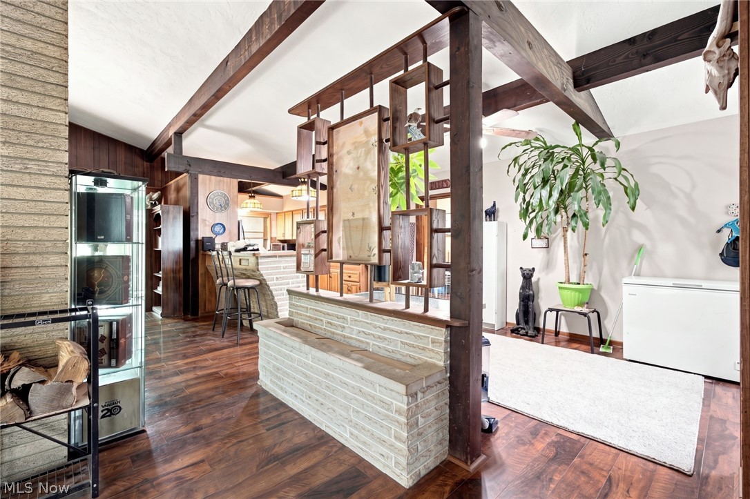Open interior with exposed beams, dark wood floors, brick half wall, and bar counter.