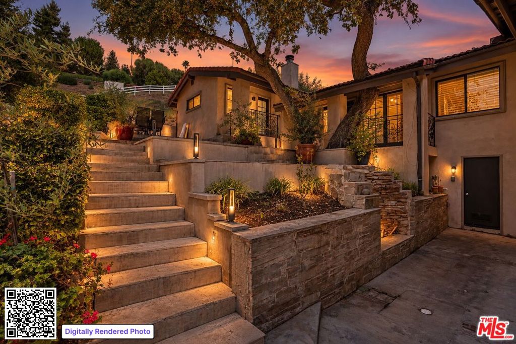 Home exterior with illuminated stone steps and landscaping beneath a colorful dusk sky.