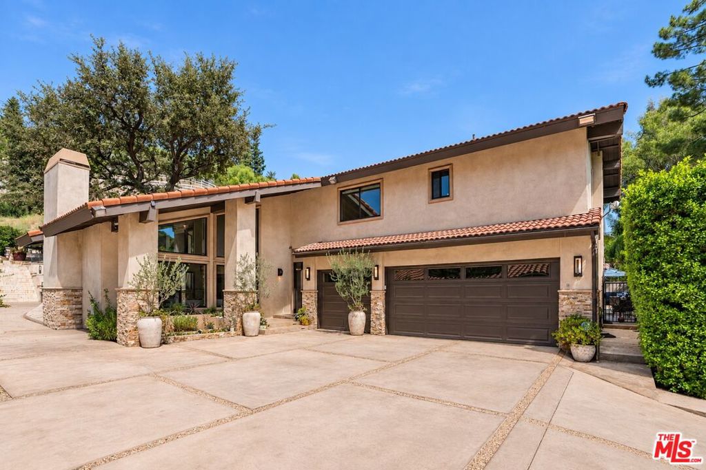 Two-story stucco home with a tiled roof, stone accents, and a wide driveway.