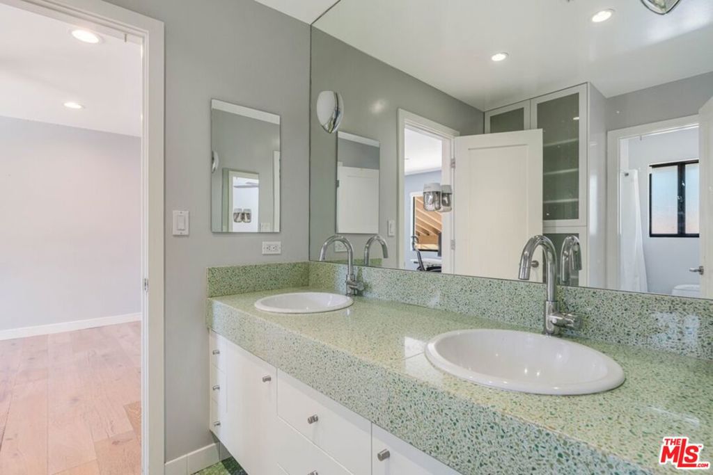 Bathroom with a double-sink vanity, green speckled countertop, and large mirror.