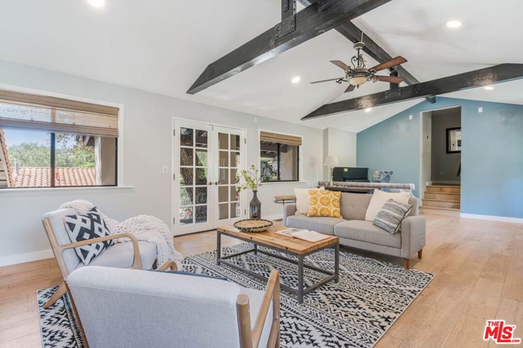 Living room with exposed dark ceiling beams, blue accent wall, and French doors.