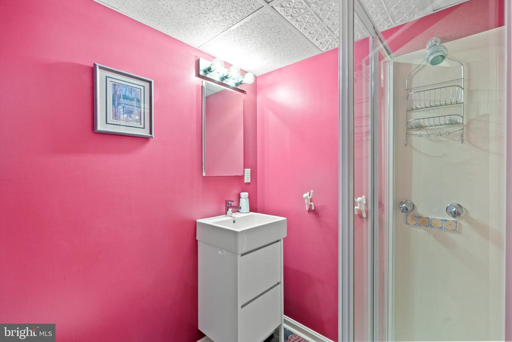 Bathroom with vivid pink walls, a white vanity, and a glass-enclosed shower.