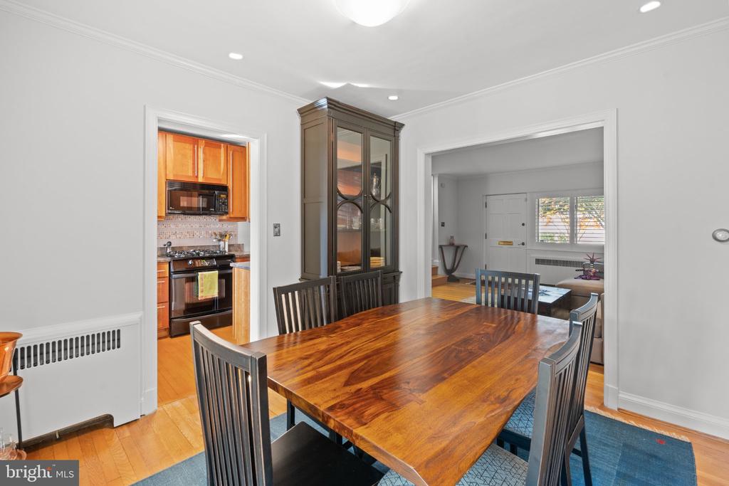 Dining room with a polished wooden table, dark chairs, and glass-front china cabinet beside the kitchen.