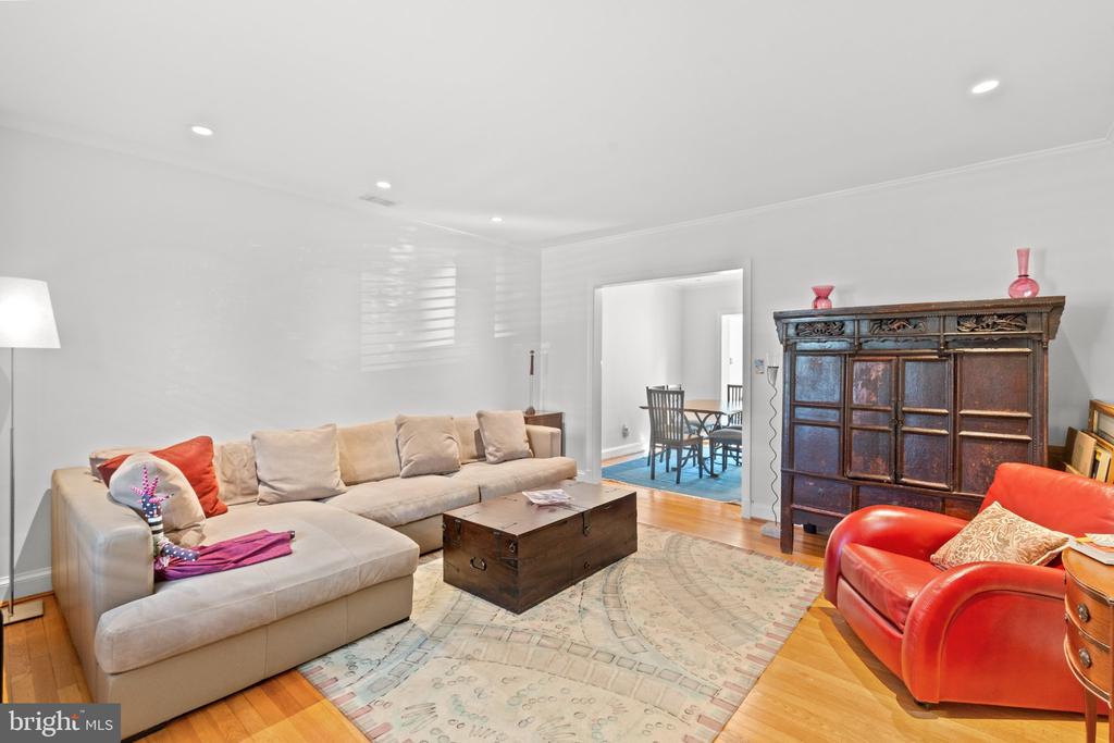 Living room with a beige sectional, red leather chairs, and an antique-style wooden cabinet.