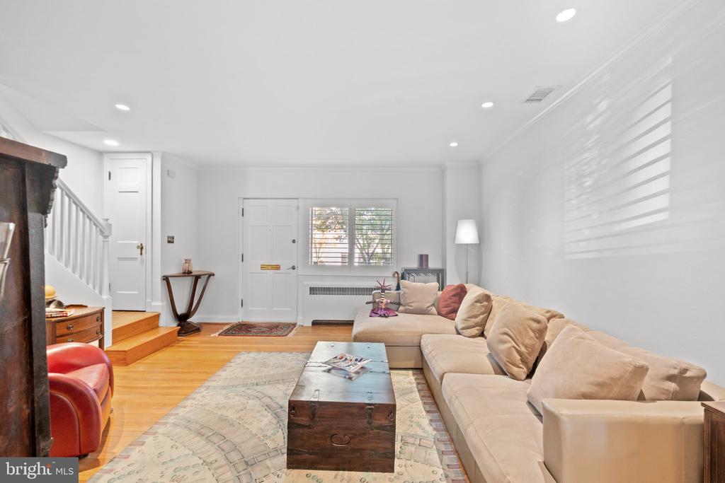 Living room with a beige sectional, wooden chest coffee table, patterned rug, and hardwood floors.