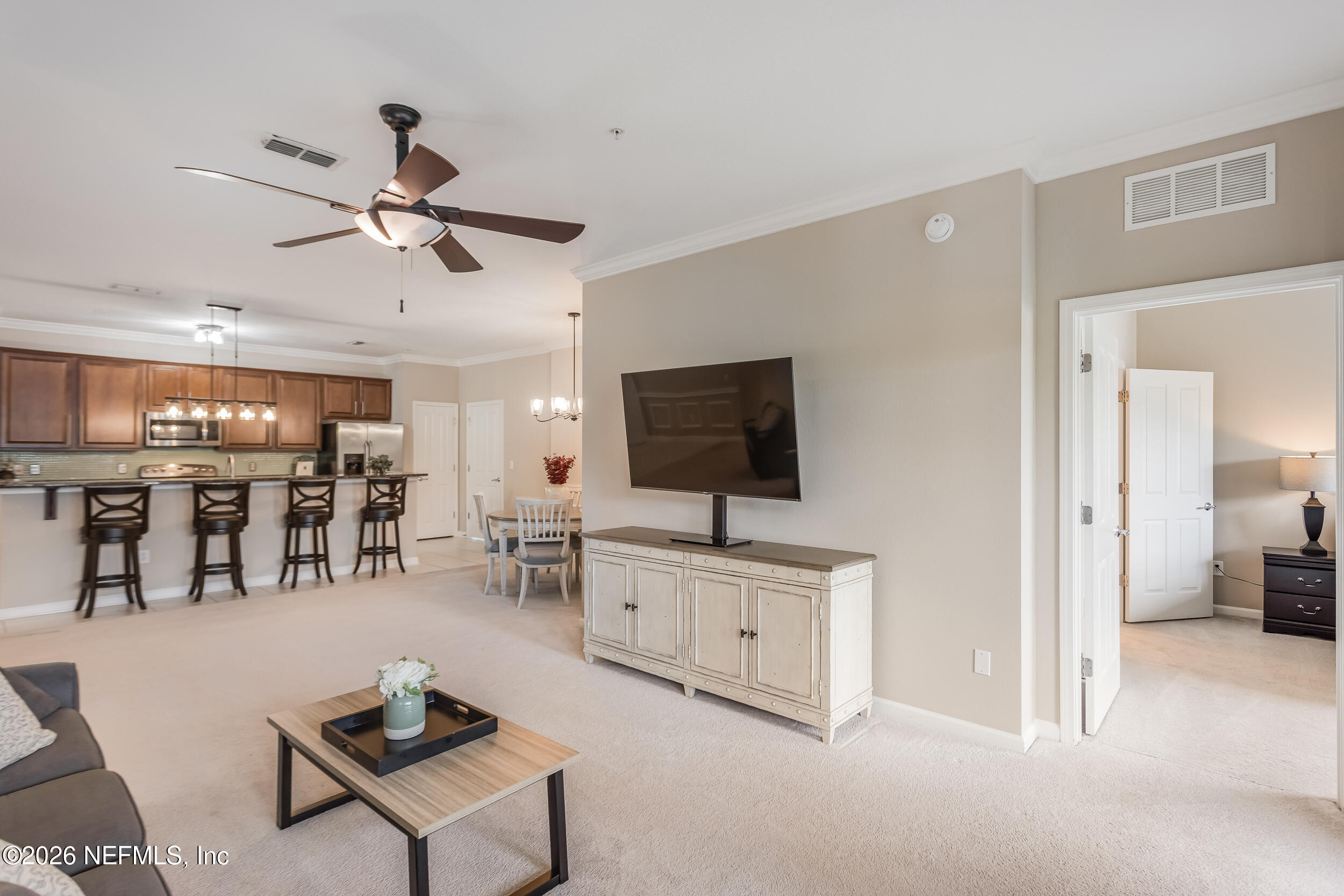 Open-plan living room with wall-mounted television, breakfast bar, and dining area.