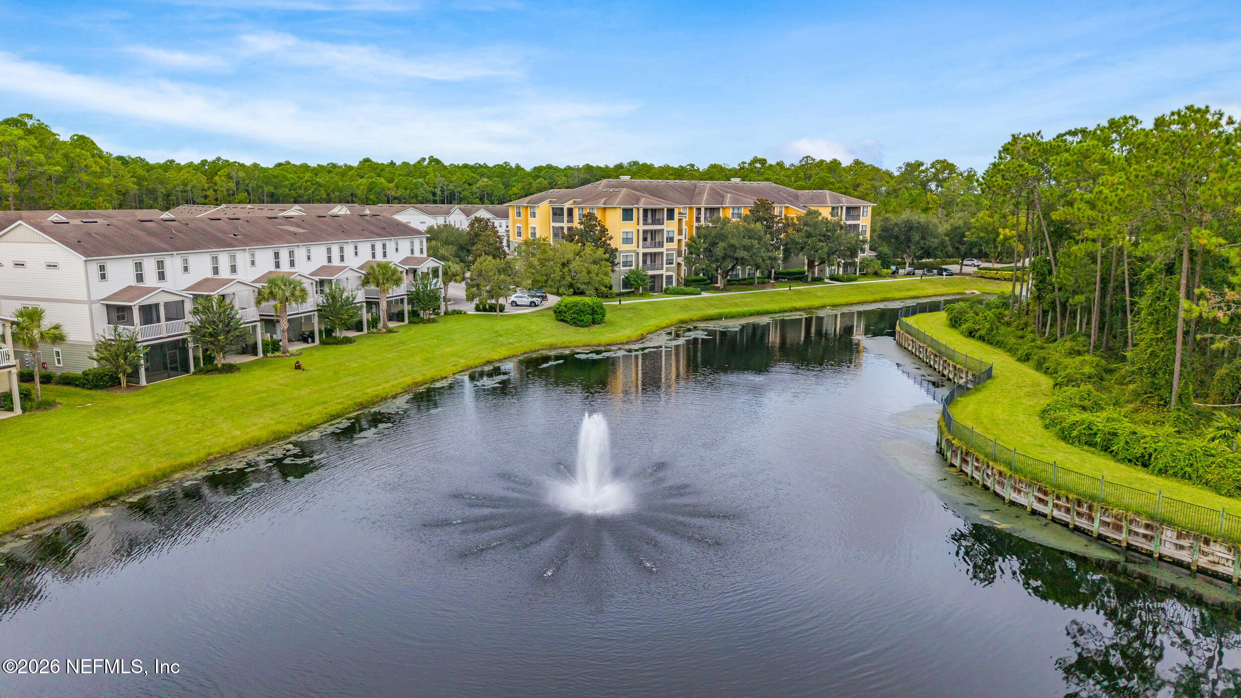 Aerial view of apartment buildings around a pond with a fountain.