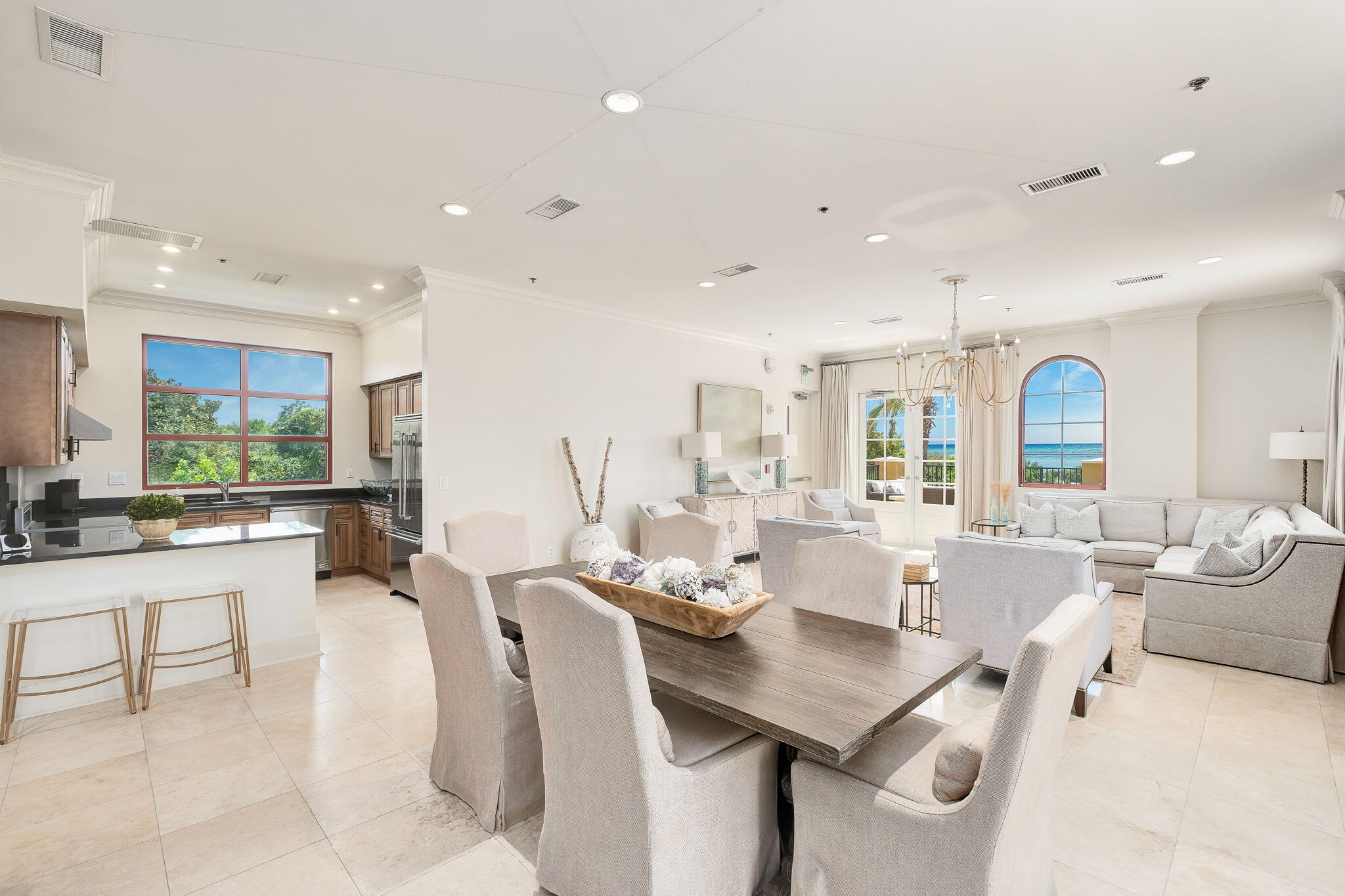 Open-plan living and dining room with an ocean view through arched windows.