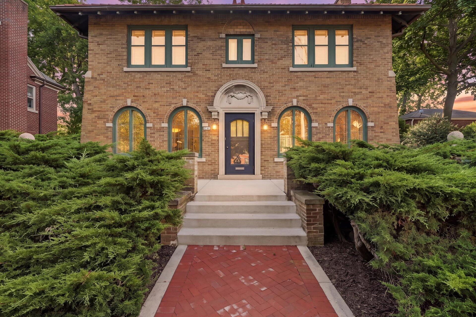 Brick home with arched windows, a blue entry door, and a red brick walkway.