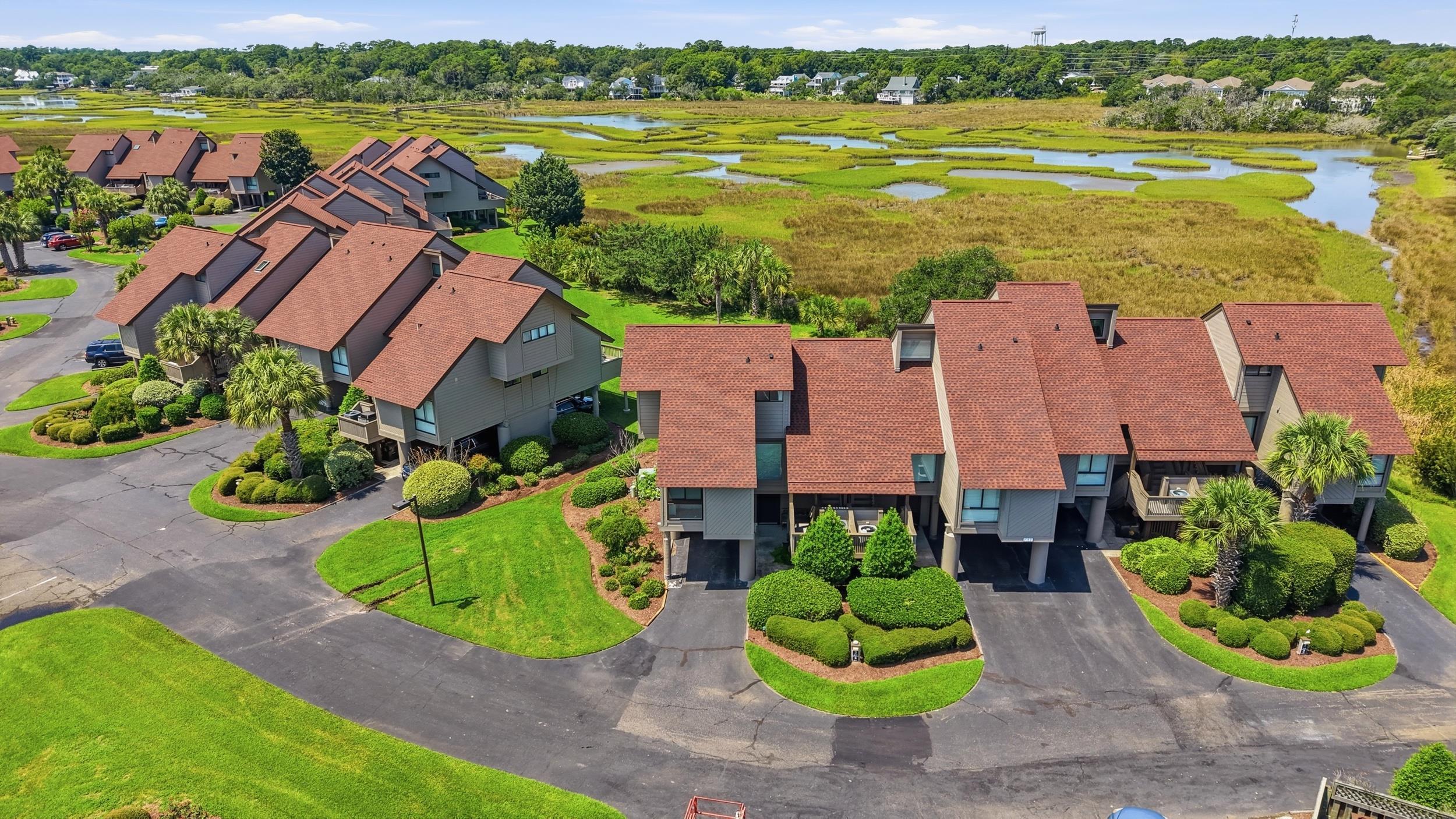 Aerial view of red-roofed coastal condos beside a salt marsh and winding waterways.