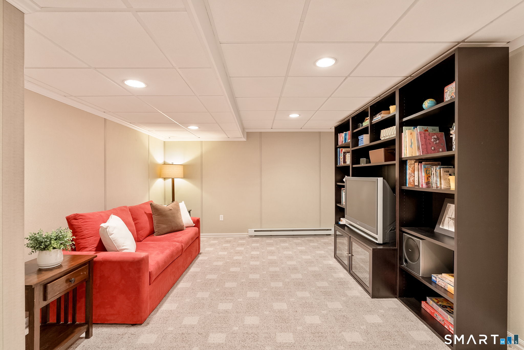 Basement family room with a red sofa and dark built-in shelving.