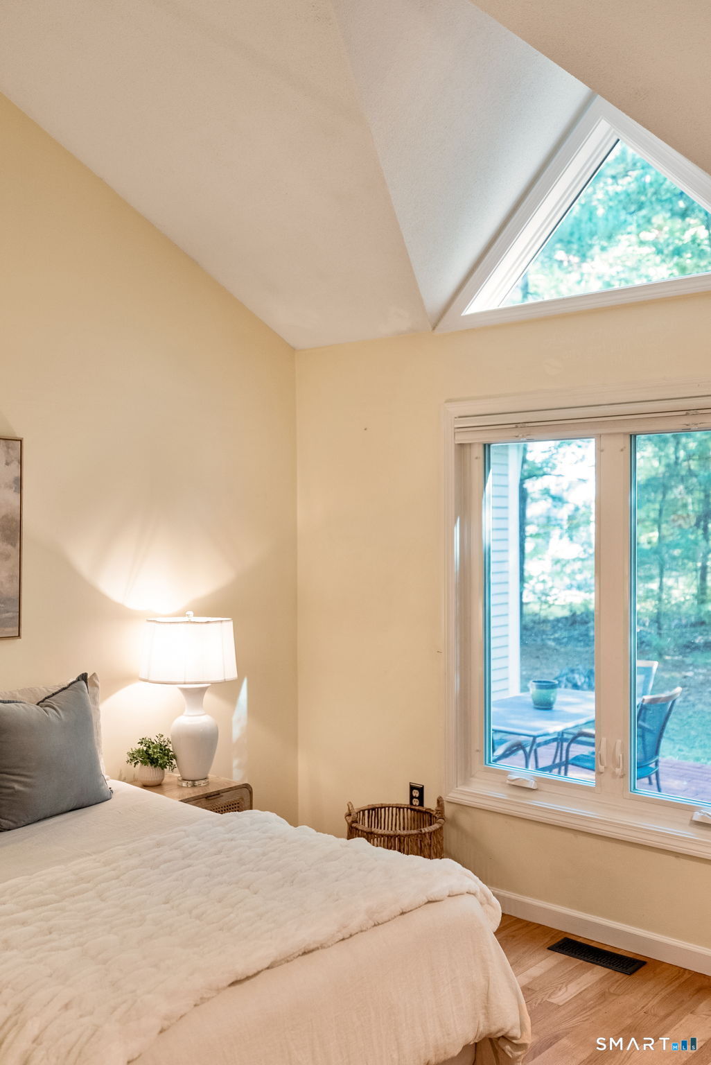 Bedroom with a vaulted ceiling, skylight, and sliding glass door to a deck.